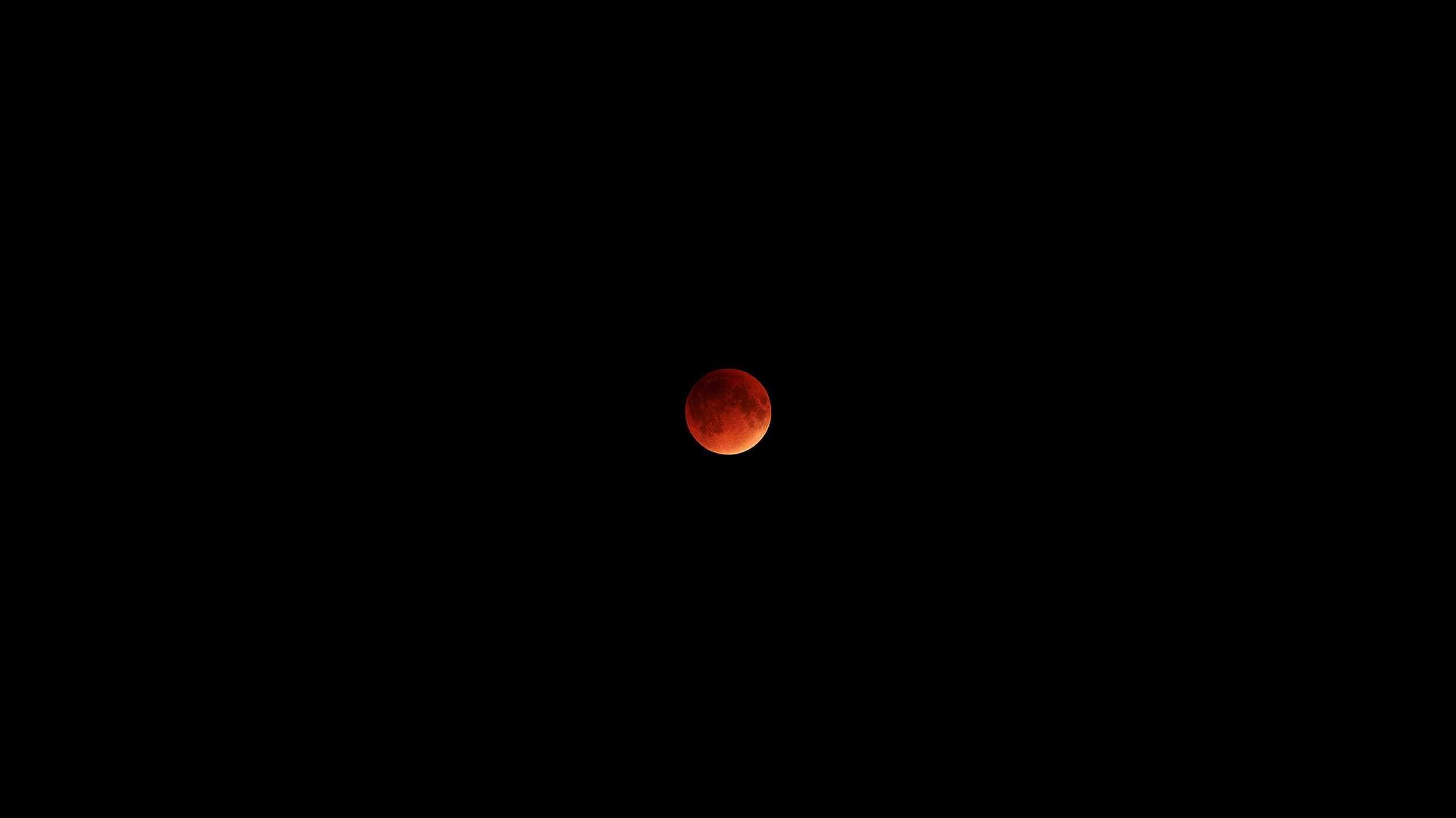 A blood moon against a pitch-black sky, its surface glowing in deep reds and oranges, conveying a mysterious and dramatic celestial event.